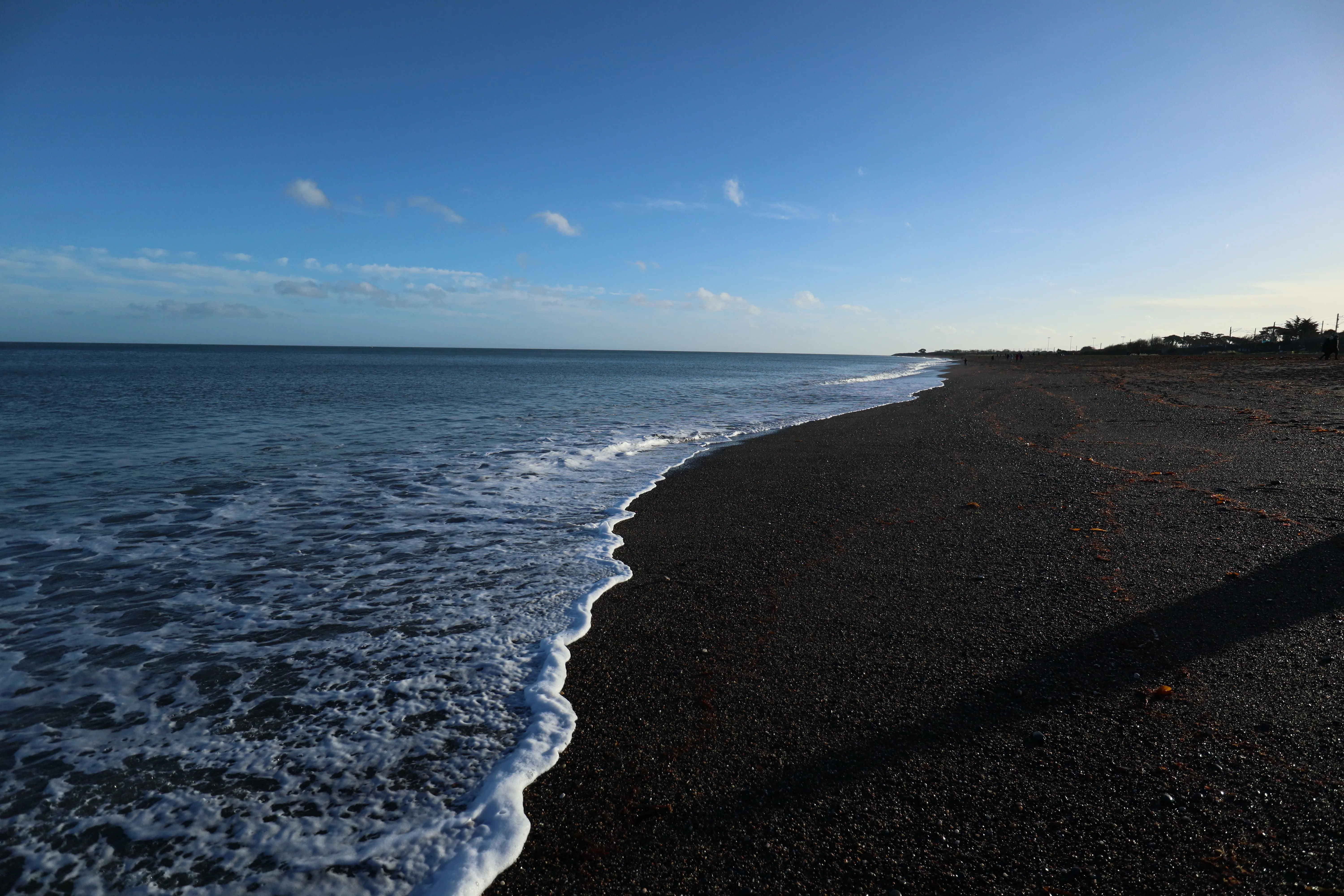 Black pebble beach under a clear sky